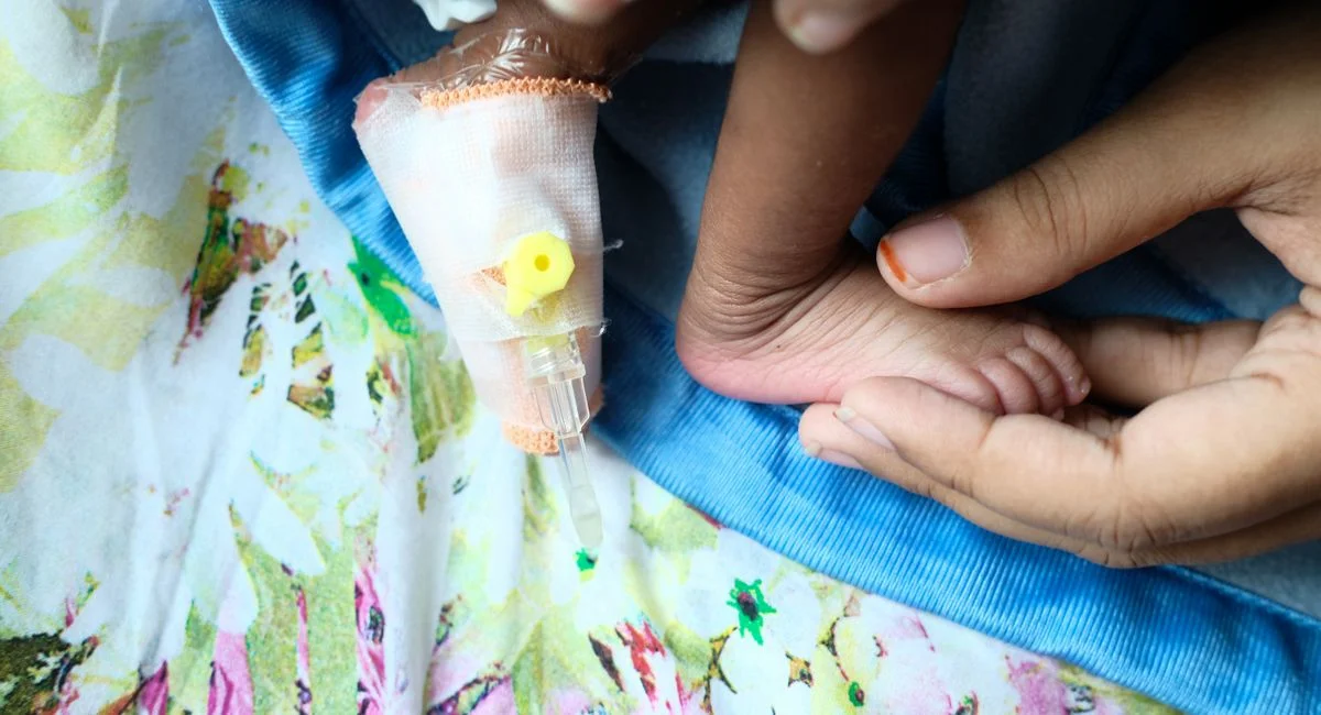 Close-up of a baby’s foot and IV bandage, symbolizing gentle care and love.