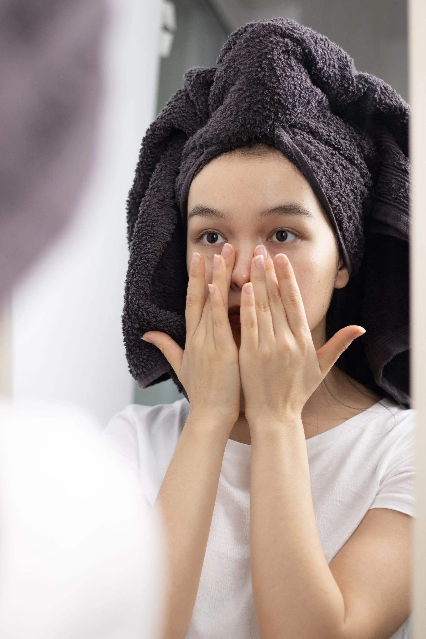 Une femme observe son visage dans un miroir avant de choisir un soin